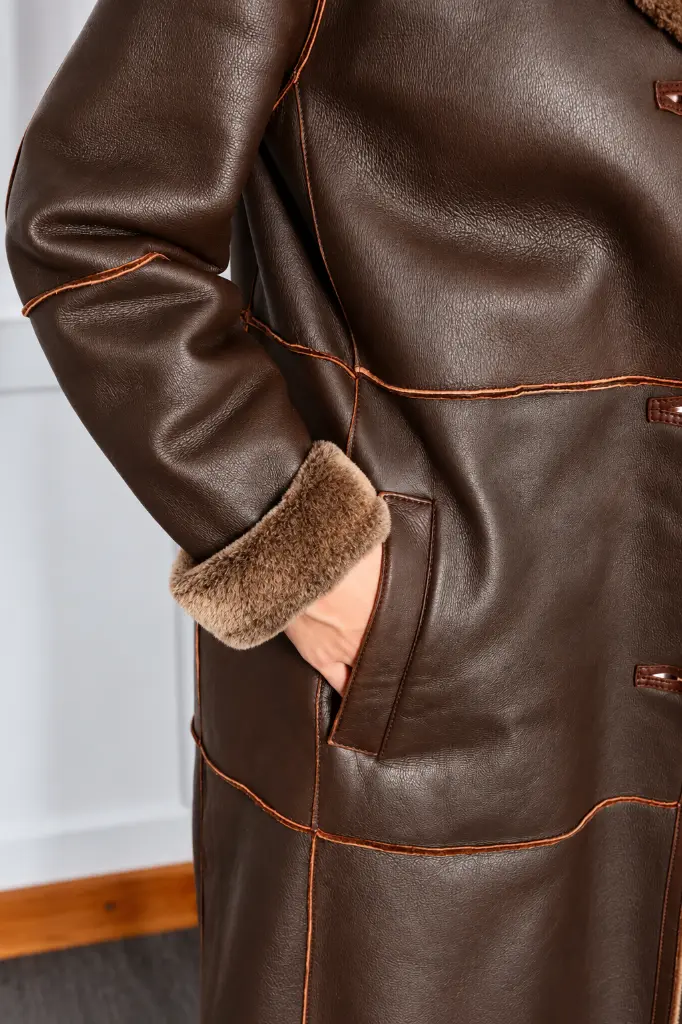 Détail de manteau en cuir brun et mouton.webp