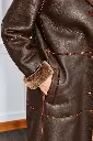 Détail de manteau en cuir brun et mouton.webp
