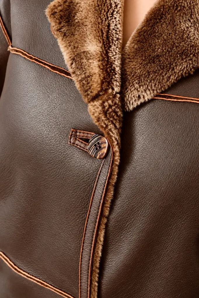 Détail texturé d’un manteau en cuir et shearling.webp