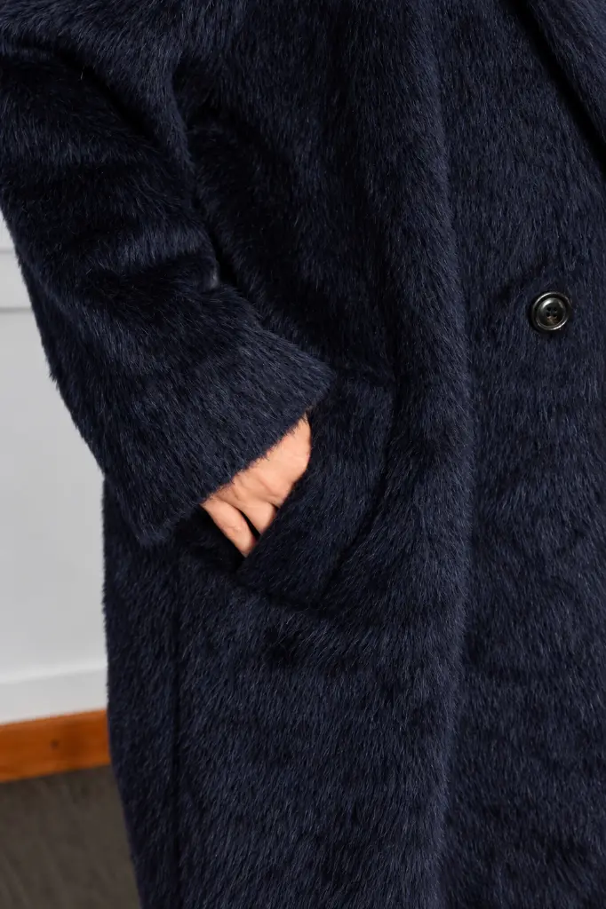 Manteau bleu marine moelleux, main en poche.webp